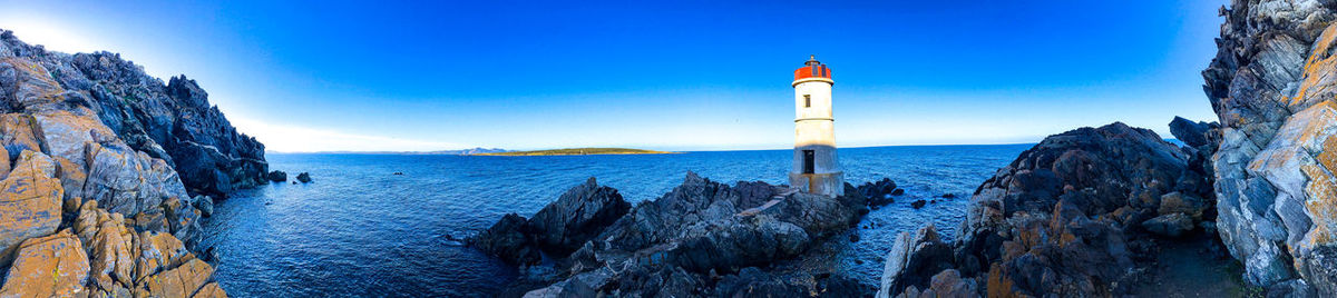 Panoramic view of lighthouse by sea against buildings