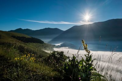 Scenic view of mountains against blue sky on sunny day