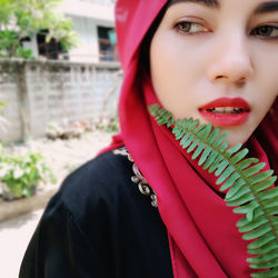 Close-up of beautiful woman with leaf looking away