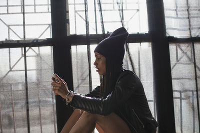 Side view of young woman looking through window