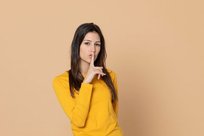 Portrait of young woman against yellow background