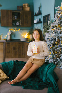 Cute girl holds a glowing toy house in her hands to decorate the house for christmas and new year