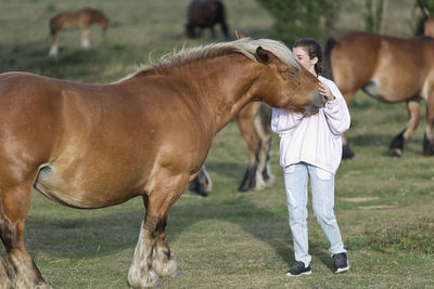 Girl with horse standing on field