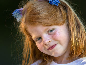 Close-up portrait of redhead girl over black background