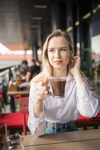 Young woman using mobile phone while sitting at cafe