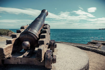 Historic cannon on fort by sea against sky