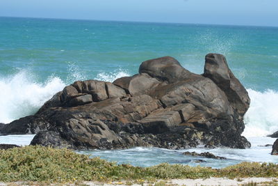 Rocks on shore by sea against sky