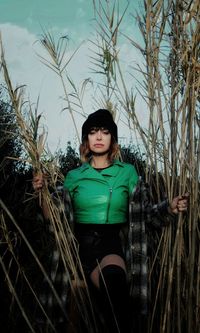 Portrait of young woman standing against plants