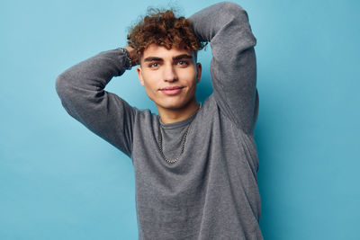 Portrait of young man standing against blue background