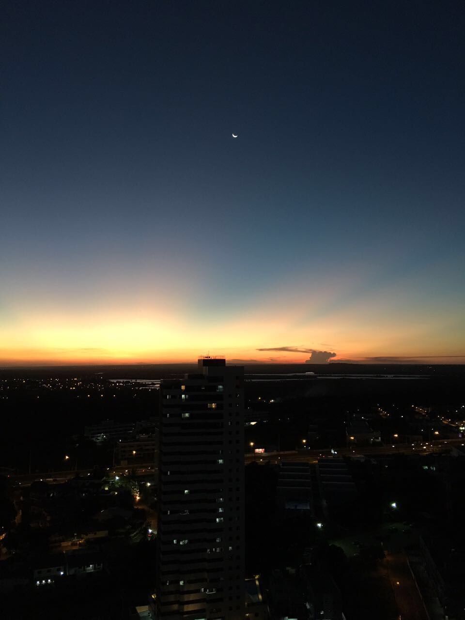 AERIAL VIEW OF ILLUMINATED CITY AGAINST SKY AT SUNSET