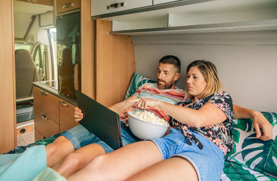 Couple watching a movie pointing tablet lying on the bed of their camper van