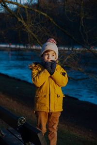 Cute boy standing on field against lake