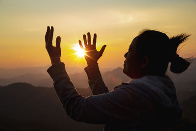 Silhouette woman on sunset background. woman raising his hands in worship. 