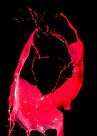 Close-up of red water splashing against black background