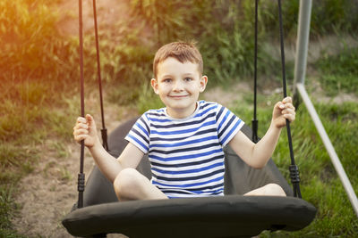 Portrait of boy holding swing at playground