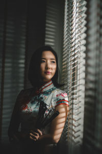 Thoughtful woman looking through window at home