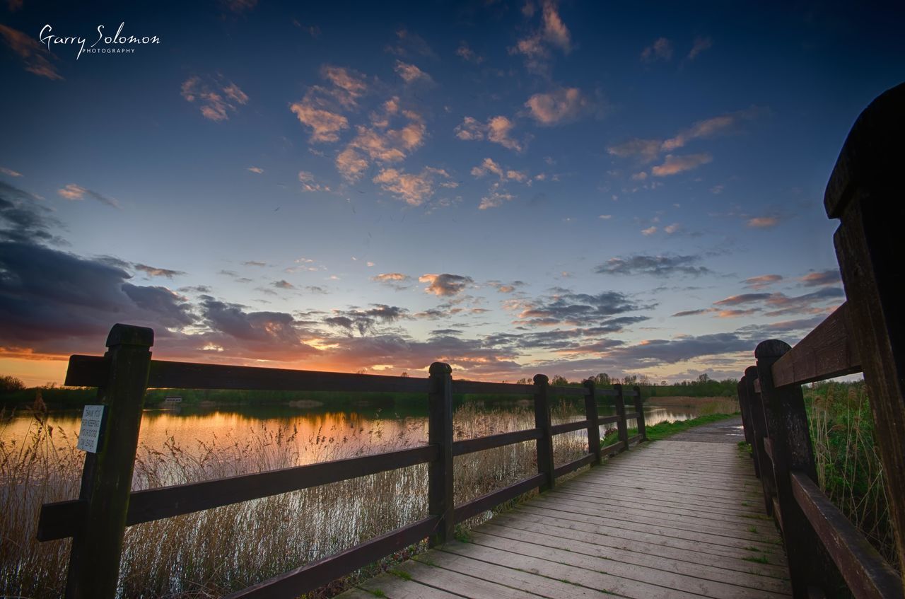 sky, railing, fence, tranquility, tranquil scene, cloud - sky, scenics, sunset, nature, landscape, beauty in nature, the way forward, cloud, field, silhouette, idyllic, outdoors, sunlight, one person, remote