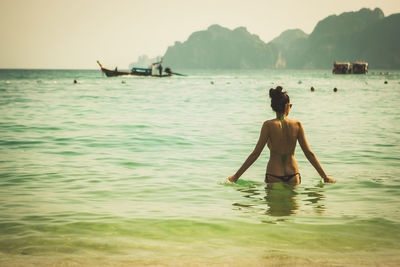 Rear view of shirtless man in sea against sky