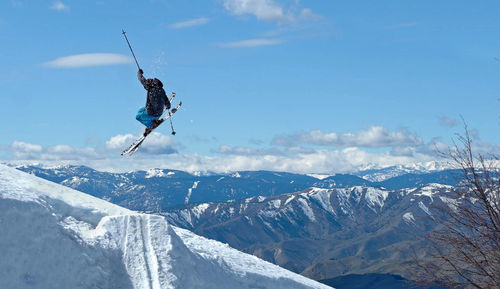 Low angle view of person performing stunt with ski against mountain