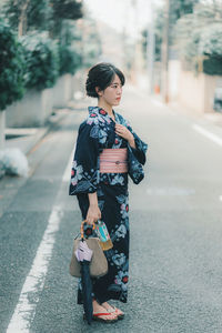 Full length of woman standing on road in city