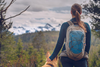 Rear view of woman with dog against snowcapped mountain