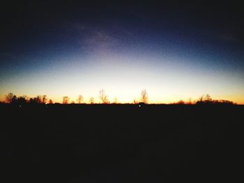 Silhouette trees on field against sky at sunset