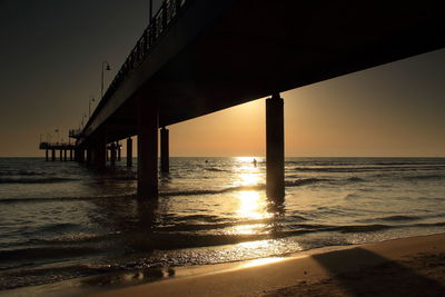 Pier over sea against sky during sunset