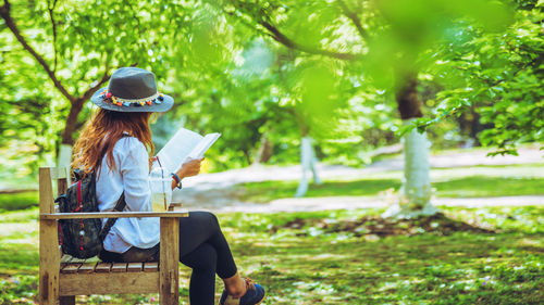 Woman sitting on land by tree