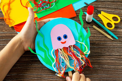 High angle view of hand holding toy on table