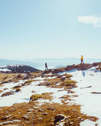 People on snowcapped mountain against sky during winter