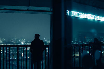 Silhouette people standing by illuminated building at night