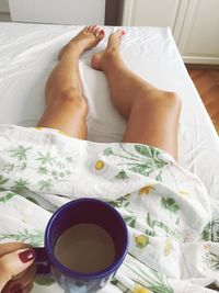 Low section of woman lying on bed at home