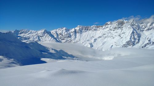 Scenic view of snowcapped mountains against blue sky