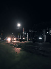 Cars on illuminated city street at night