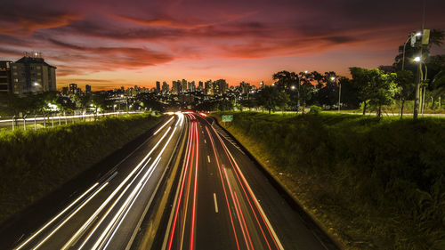 High angle view of light trails on road against sky during sunset and city background 