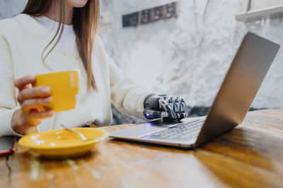 Midsection of woman using mobile phone on table