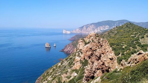 Scenic view of sea and mountains against clear blue sky