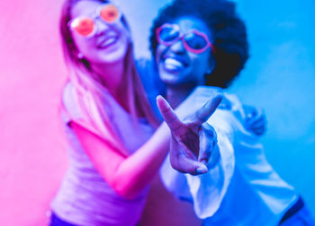 Portrait of happy lesbian couple against wall