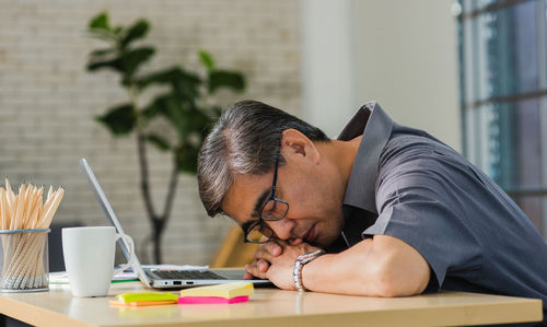 Businessman with laptop sleeping on desk in office