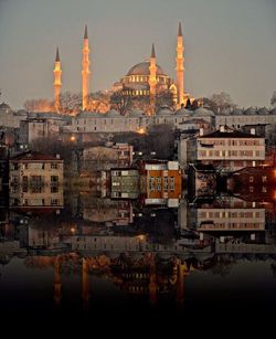 View of mosque by river against sky in city