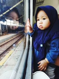 Portrait of cute girl sitting on train window