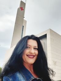 Portrait of smiling young woman against blue sky