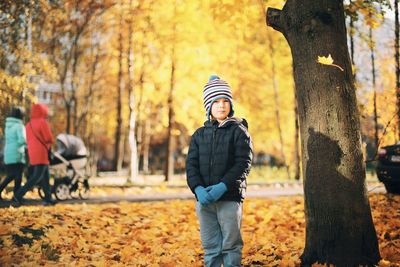 Full length portrait of boy on snow covered land during autumn