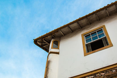 Low angle view of building with open window against sky