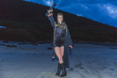 Portrait of woman standing at beach at dusk