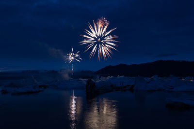 Firework display over river against sky at night