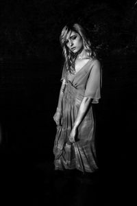 Portrait of young woman with eyes closed standing against black background