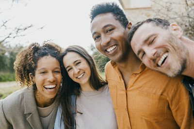 Portrait of happy multiracial male and female friends at backyard