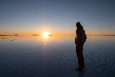 Silhouette man standing on beach against sky during sunset