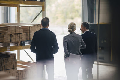 Rear view of business people discussing while standing at industry